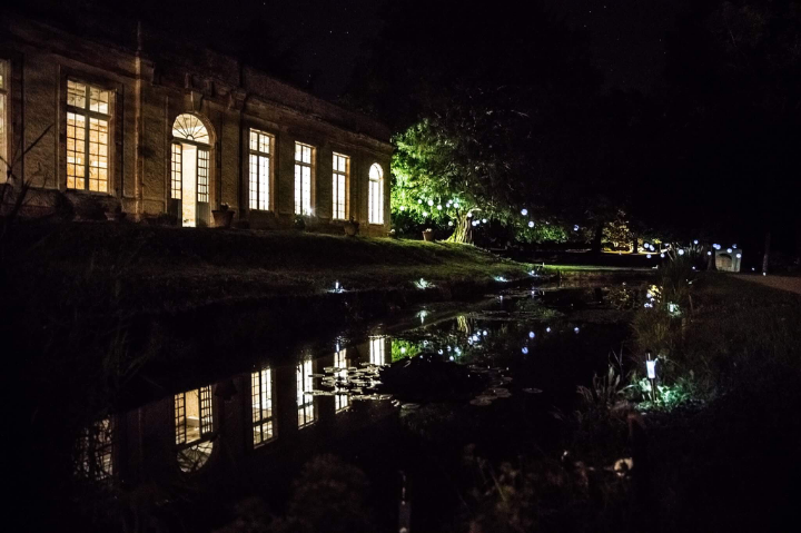 Vue de nuit de l'extérieur de l'Orangerie et du bassin avec le reflet des lumières